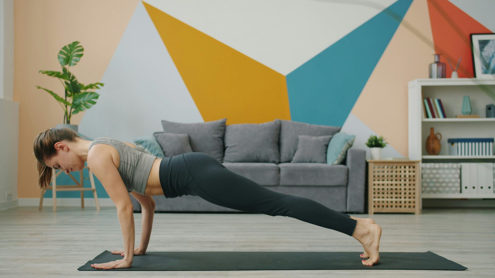 A woman holding a straight-arm plank on a mat in a living room